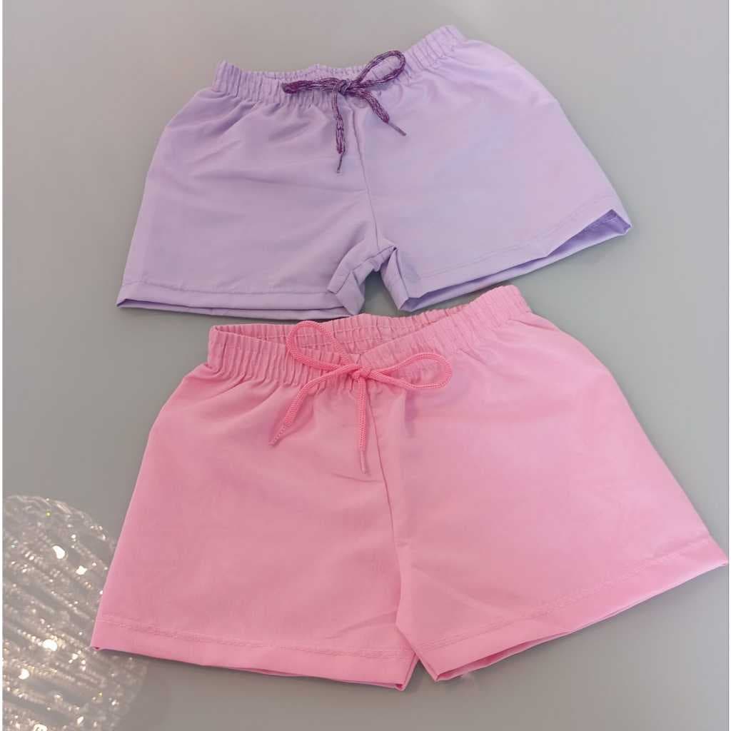 Shorts menina em tactel, ideal para praia, revela estampa em contato com água.